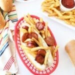 Chourico and Fries Grinder is in a red basket with extra fries, chourico, and bread nearby.