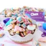 Colorful Unicorn Chex Snack Mix in a Bowl with small pieces of the mix on a white table.