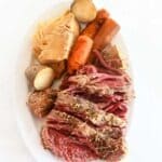 Croned beef, cabbage, carrot, and potato on a white oval dish.