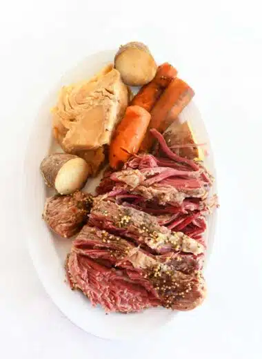 Croned beef, cabbage, carrot, and potato on a white oval dish.