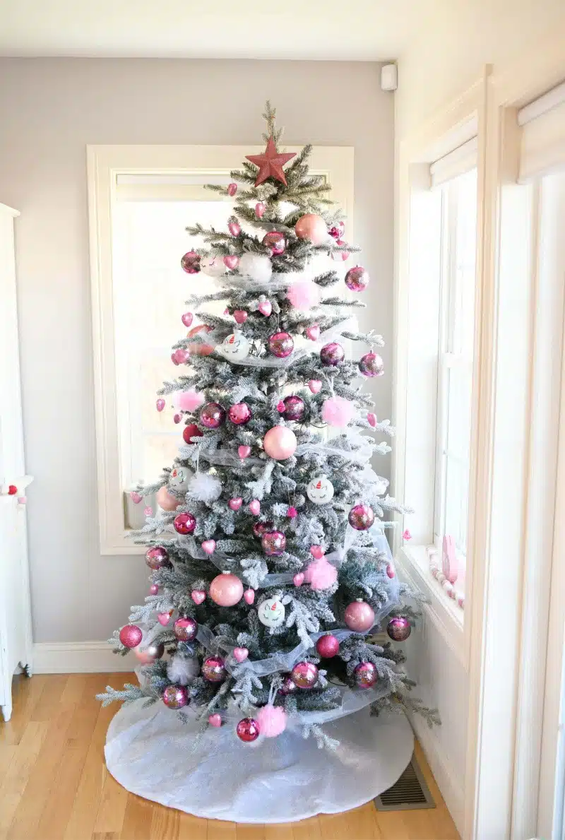 Valentine's Day Tree in a grey room. There is pink and white ornaments on this green tree. 