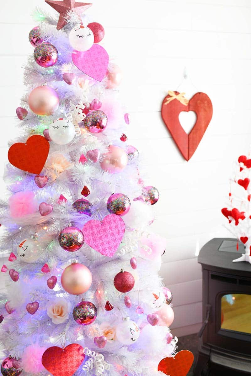White Valentines Day Tree in a white living room. There is a red heart on the wall. 