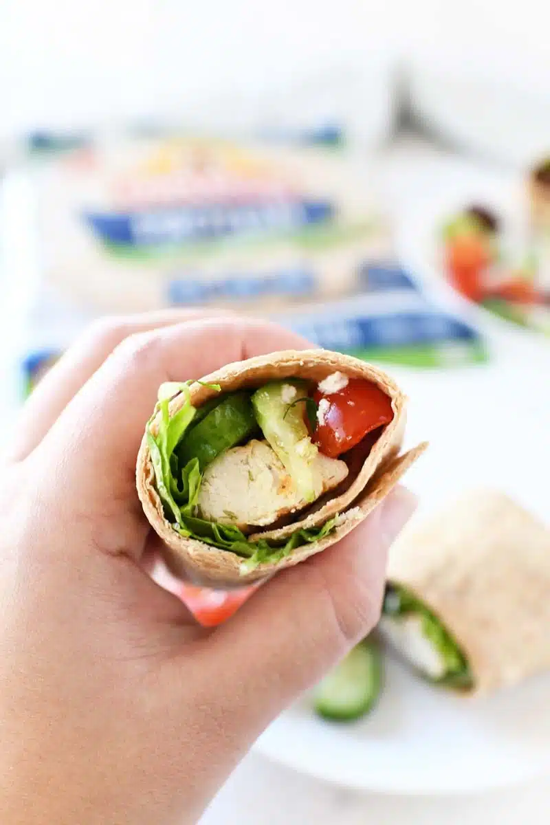 Greek Wrap recipe in someone's hand showing inside the wrap.