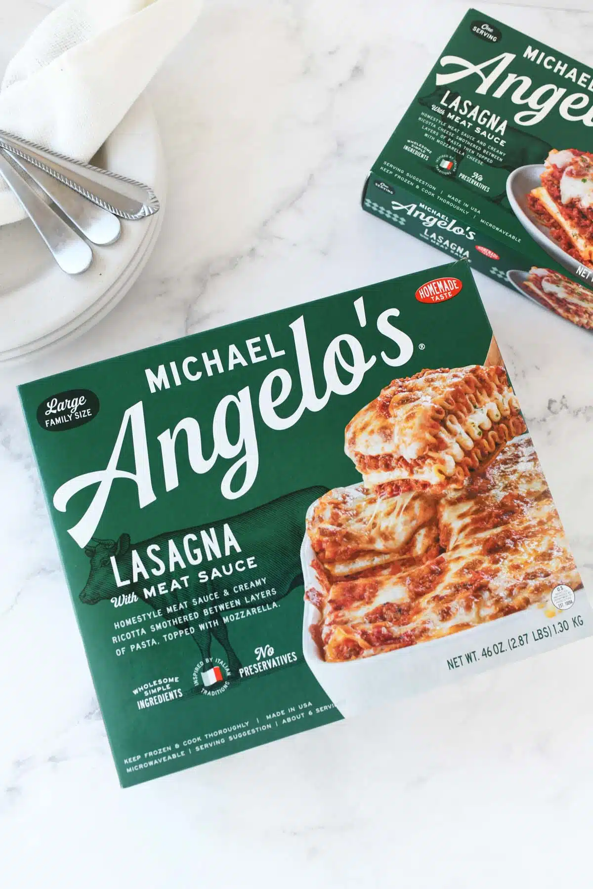 Michael Angelo's Large Family Size product box on a white marble table with plates and cutlery.