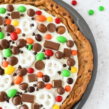 Chocolate Chip Cookie Pizza in a pan topped with white chocolate candy pieces.