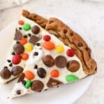 2 colorful slices of chocolate chip cookie pizza on a white plate.