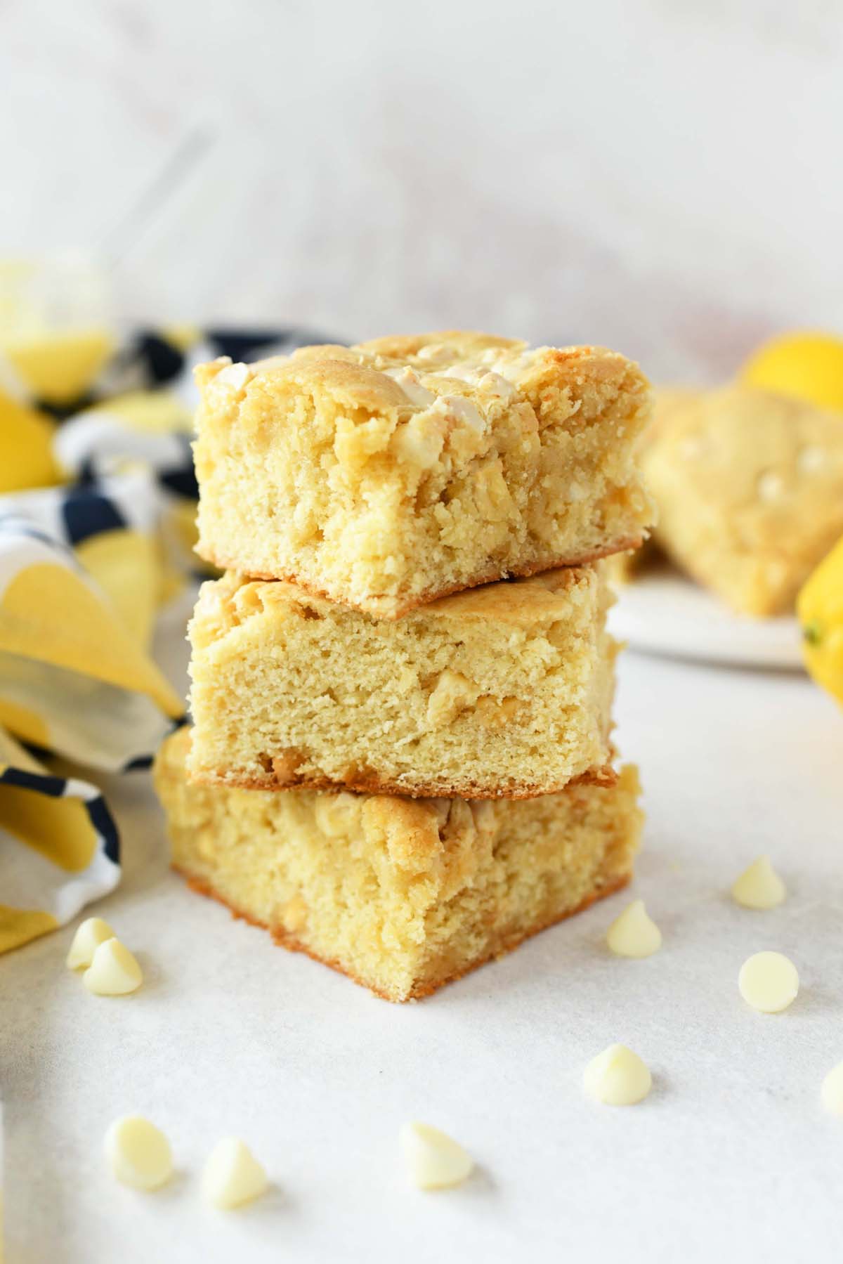 Lemon Blondies stacked on a white marble table with mini white chocolate chips.