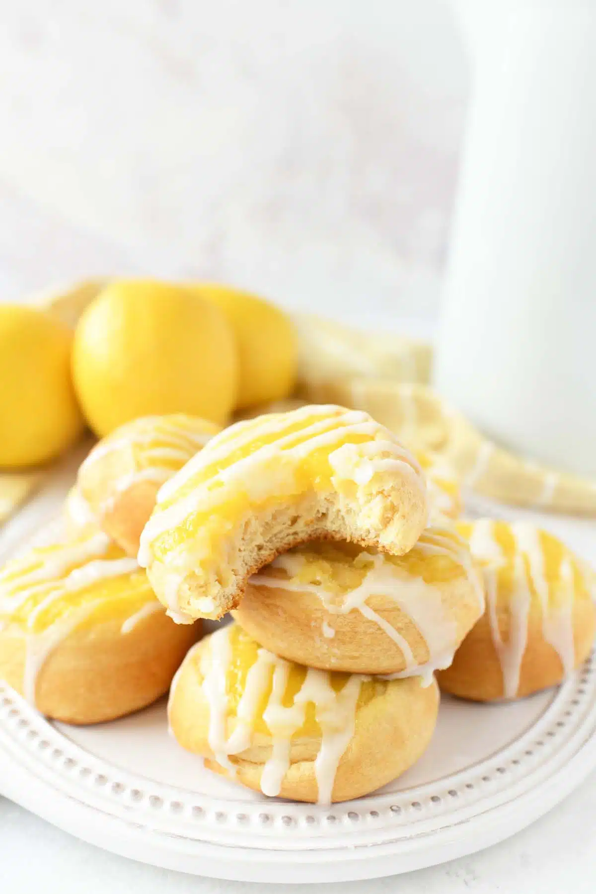 Lemon Danish with a bite taken out of one stacked on a plate.