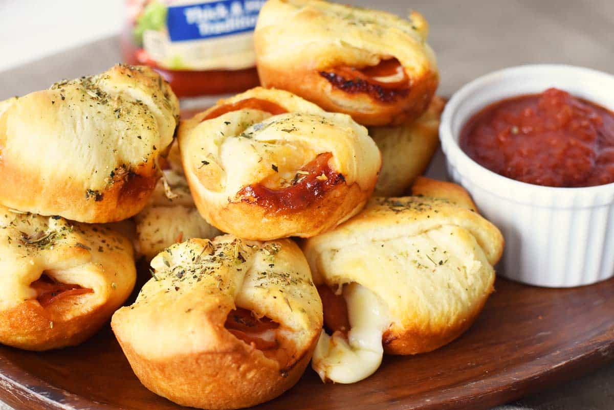 Pepperoni Cheese Bites on a wooden platter with marinara sauce on a plate.