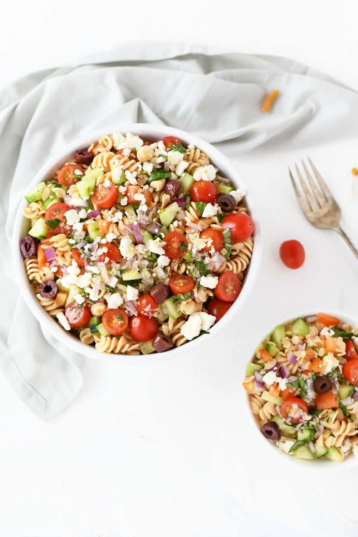 Colorful Greek Pasta Salad in a large and small bowl with a fork.