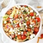 A colorful bowl of Greek salad with feta cheese in a white bowl.