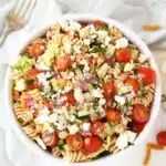 A colorful bowl of Greek salad with feta cheese in a white bowl.