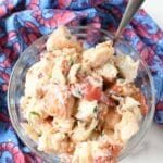Lobster salad in a large clear bowl with a silver spoon.