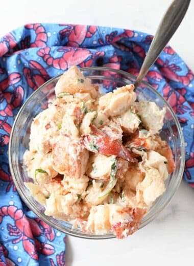 Lobster salad in a large clear bowl with a silver spoon.