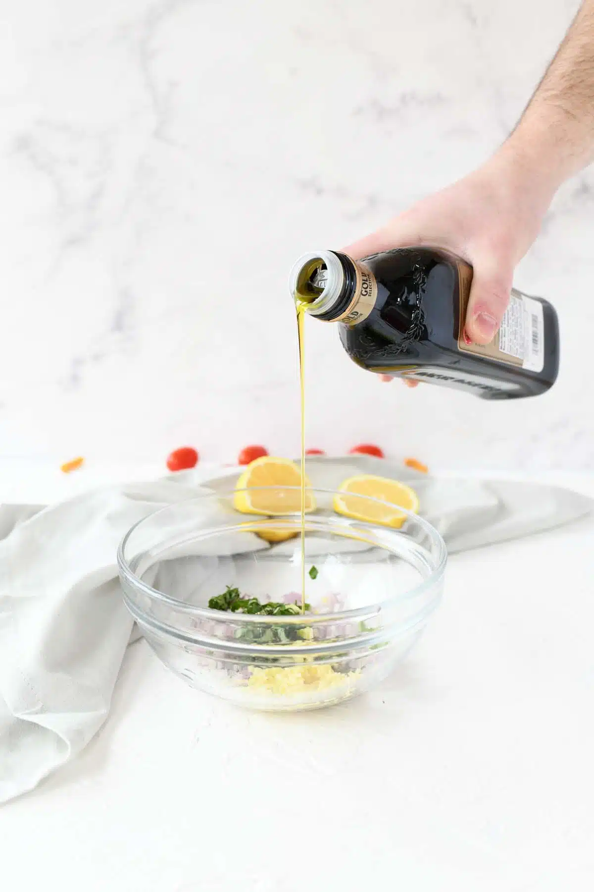 Pouring olive oil into a bowl of veggies.