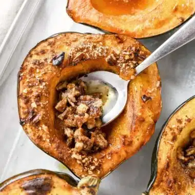 A silver spoon tucked inside a pecan filled acorn squash.