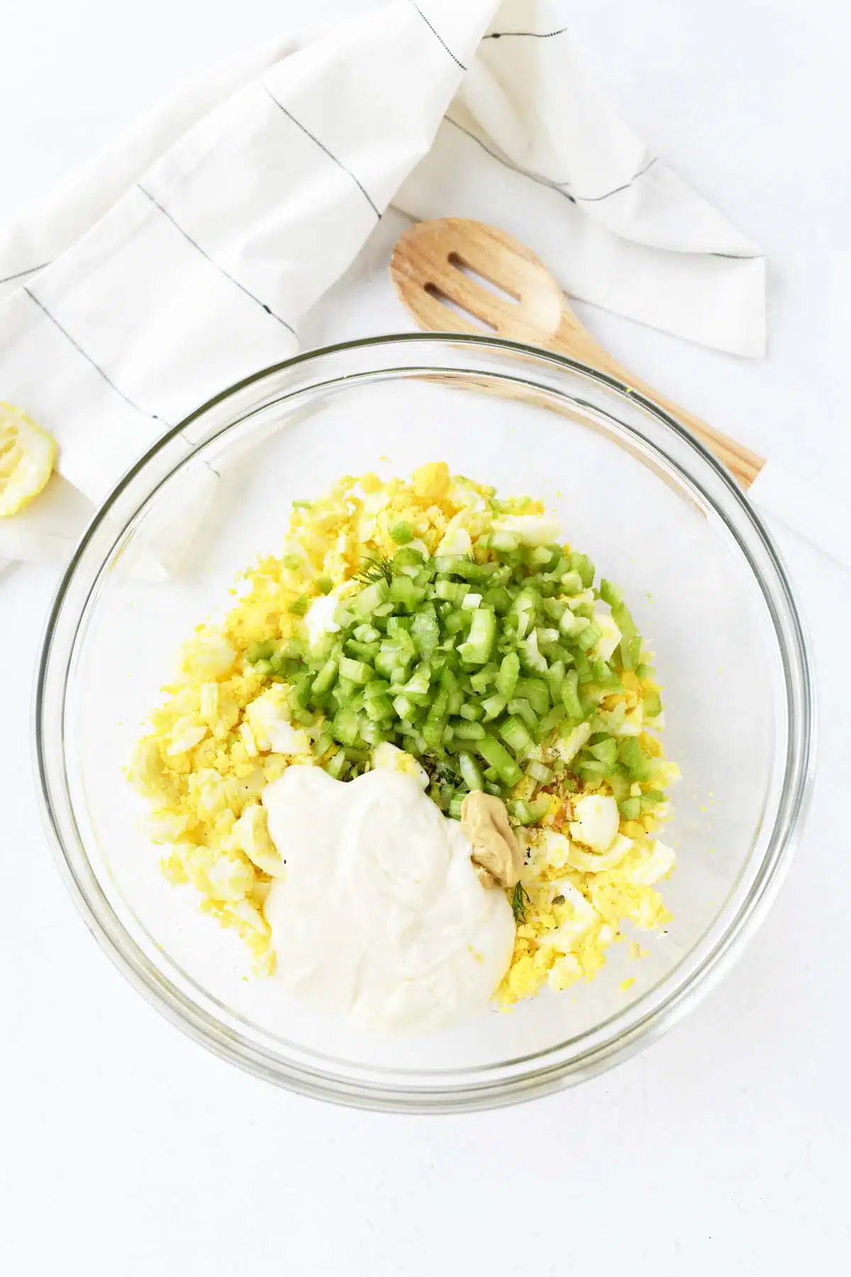 Egg salad ingredients in a bowl on a white table.