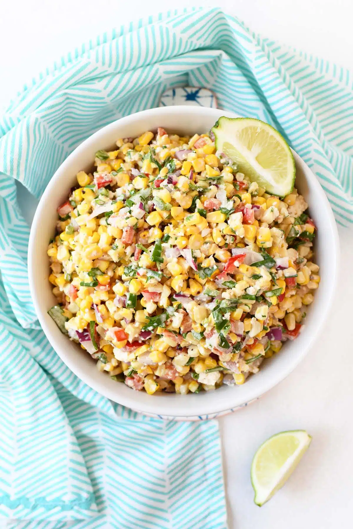 Mexican Corn Salad with cotija cheese in a white bowl with a blue napkin.