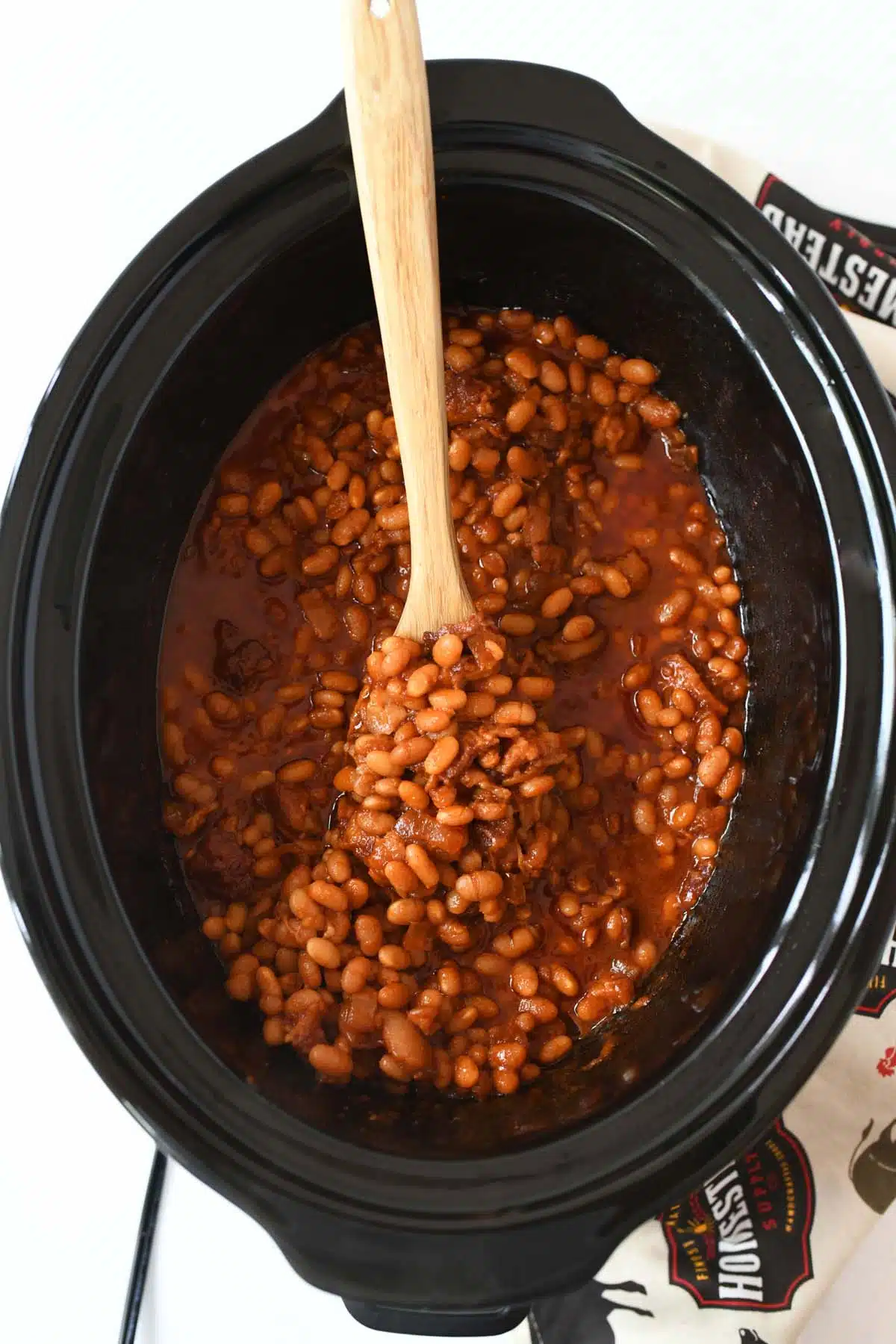Slow Cooker Boston Baked Beans with a wooden spoon.