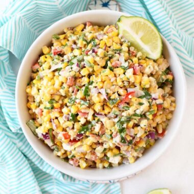Mexican Corn Salad with cotija cheese in a white bowl with a blue napkin.