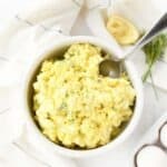 Egg salad in a white bowl with a spoon.