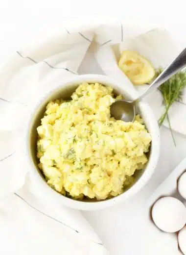 Egg salad in a white bowl with a spoon.