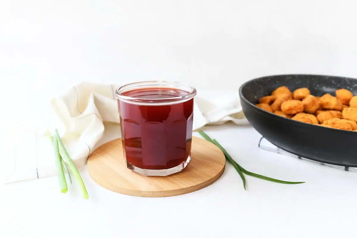 A glass jar of Sweet and Sour Sauce on a white table.