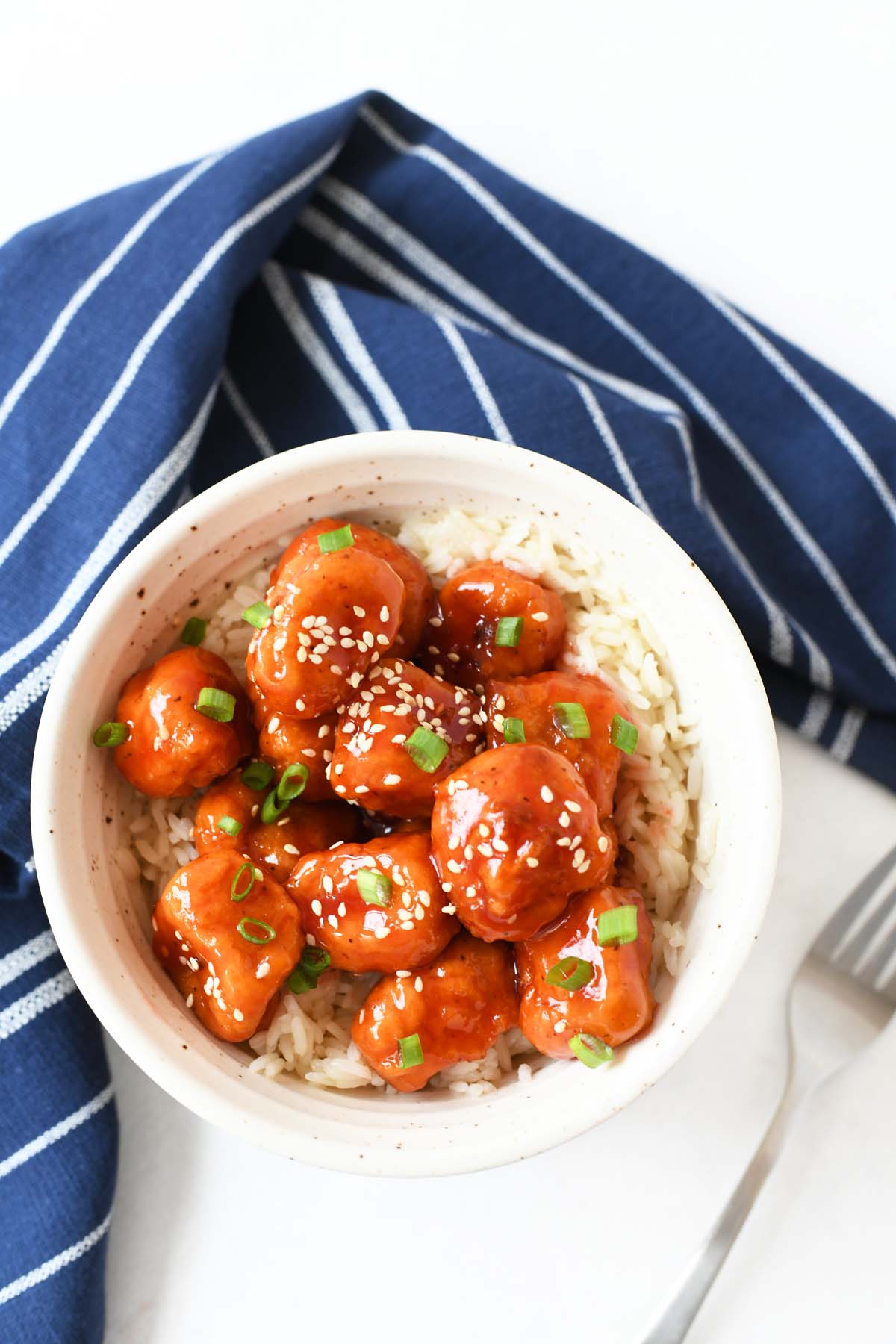 Sweet and Sour Sauce Chicken in a white bowl with a blue napkin.