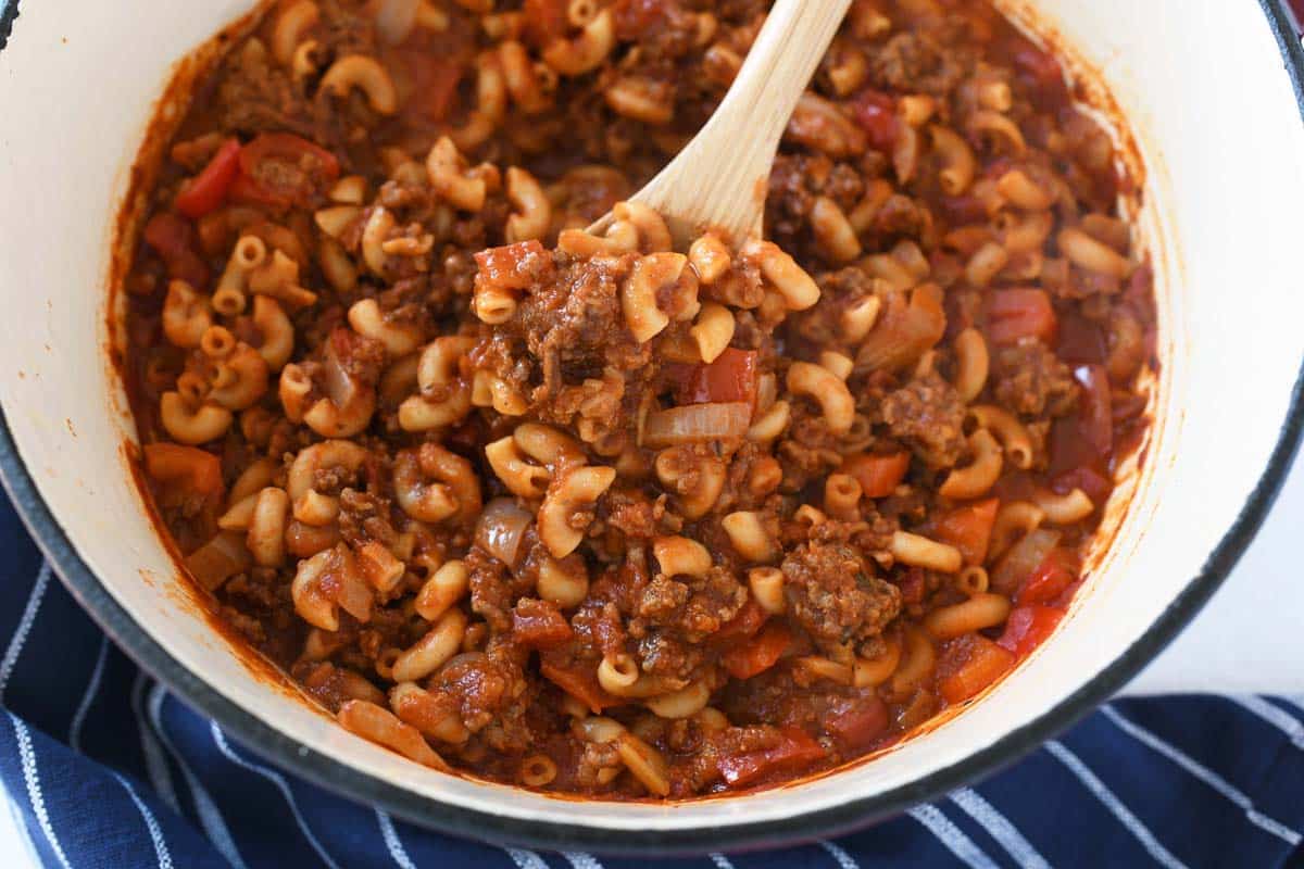 American Chop Suey in a pan with a wooden spoon.