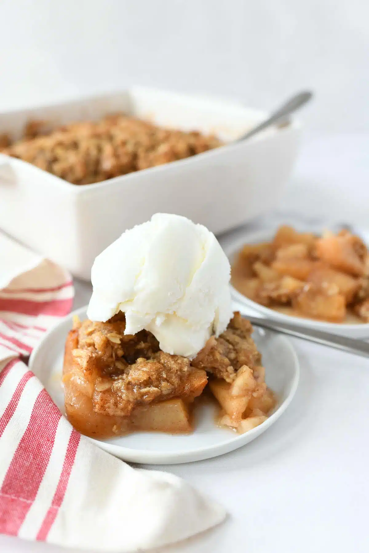 A small bowl of apple crisp with a dollop of vanilla ice cream on top.