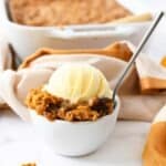 A bowl of warm pumpkin crisp with vanilla ice cream.