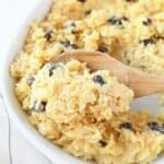 Eggnog Rice pudding in a white bowl with a wooden spoon.