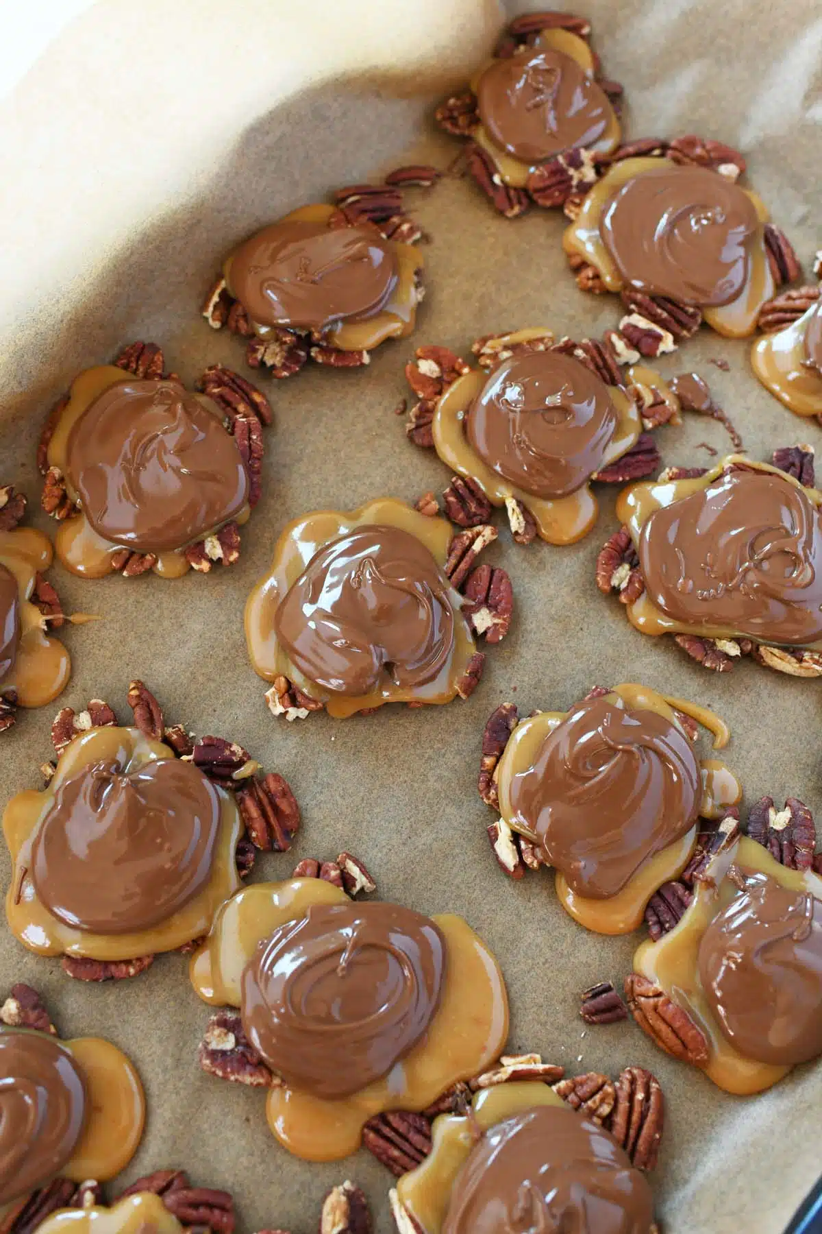 Chocolate topped pecans on a baking sheet.