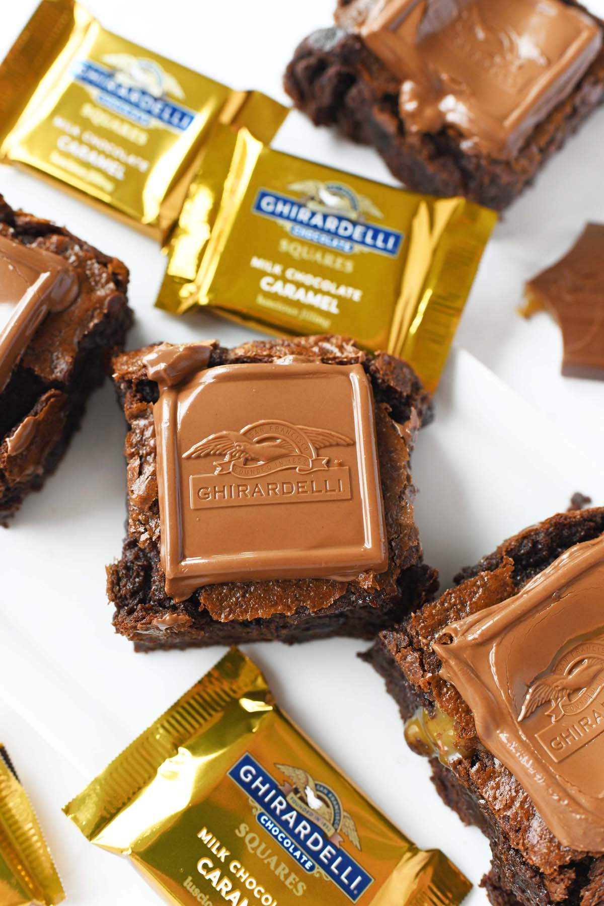 Ghirardelli caramel brownies on a white plate with wrapped chocolates.