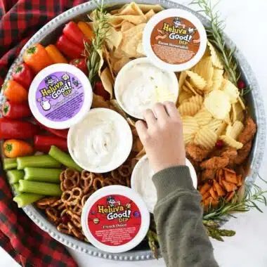 A boy with a green sweatshirt dipping a chip.