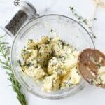Herbed Compound butter in a glass bowl with a wooden spoon.