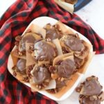 Homemade turtle candies on a white plate with a red plaid napkin.