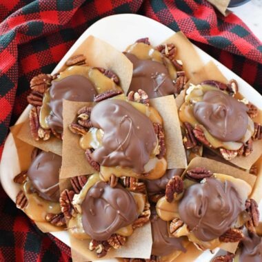 Homemade turtle candy on a white platter with a red plaid napkin.