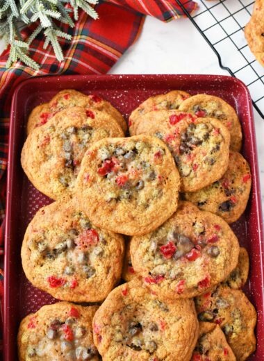A red baking sheet with chewy chocolate cherry cookies on top.