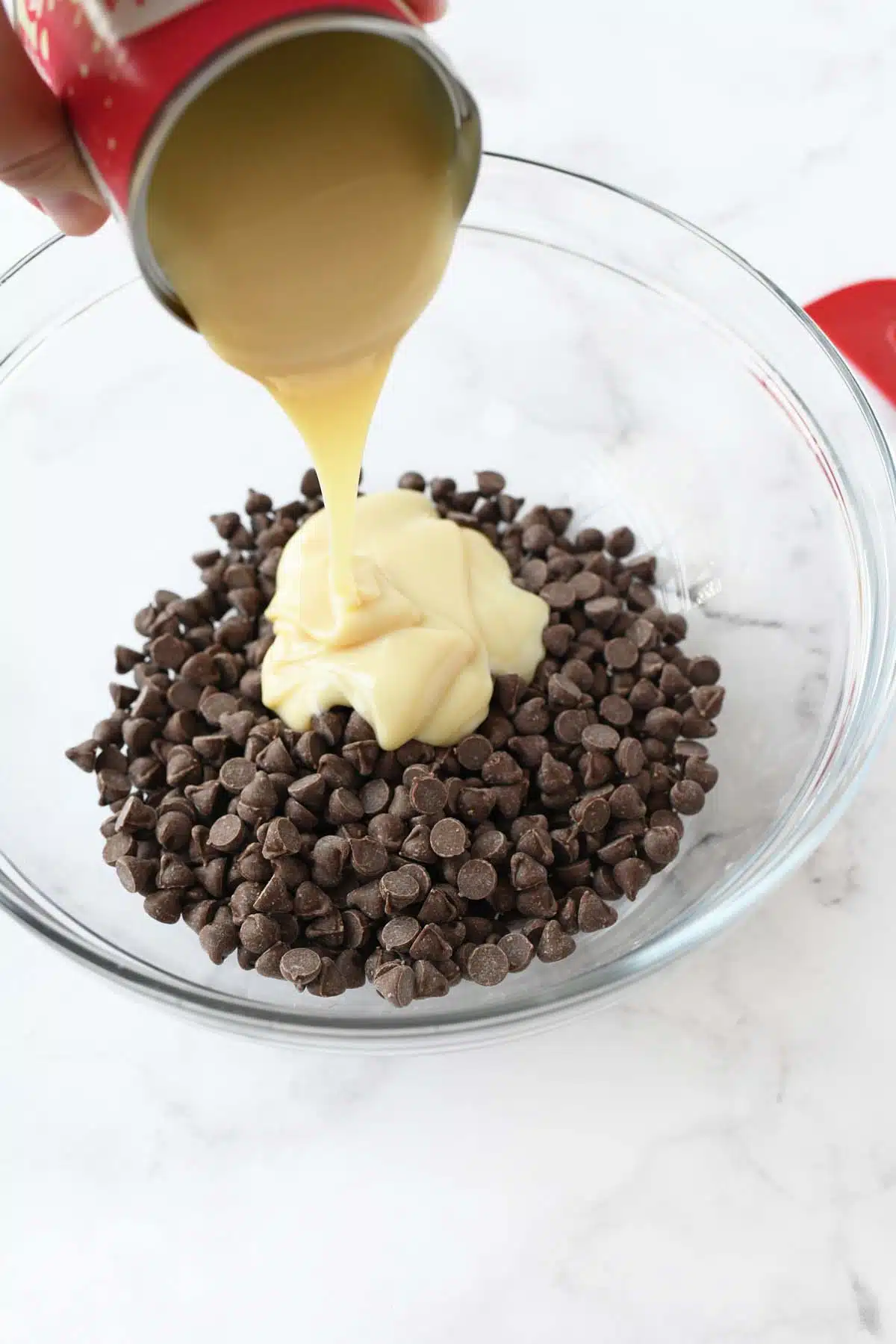 Sweetened condensed milk and chocolate chips in a glass bowl.