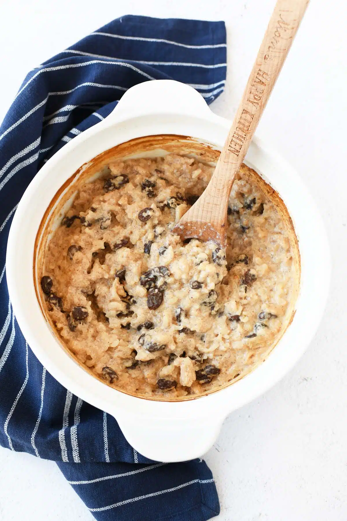 Baked rice pudding with raisins and a wooden spoon.