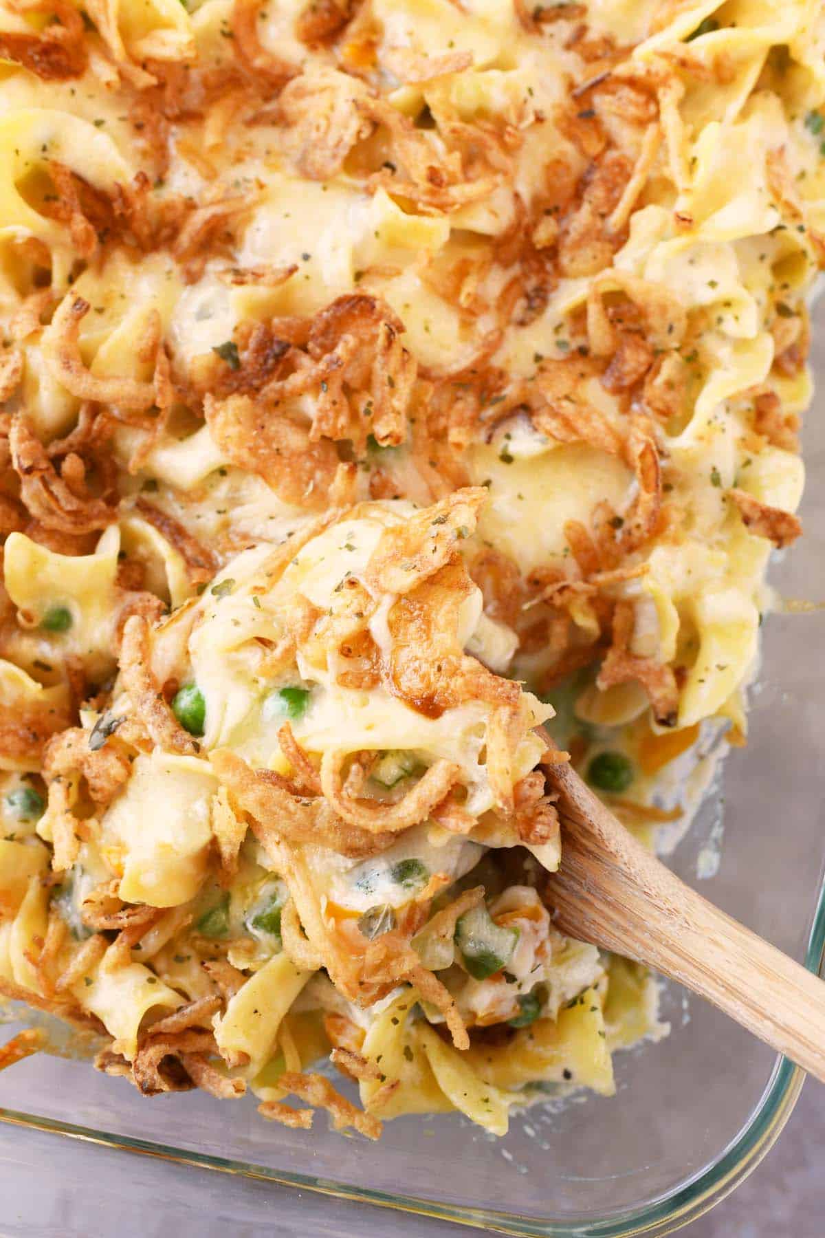 Golden brown tuna noodle casserole on a wooden spoon.