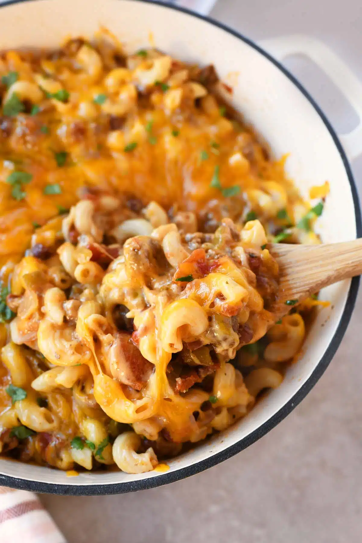 Cheesy chili mac on a wooden spoon.