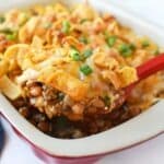 Frito pie with cheese on a spoon.