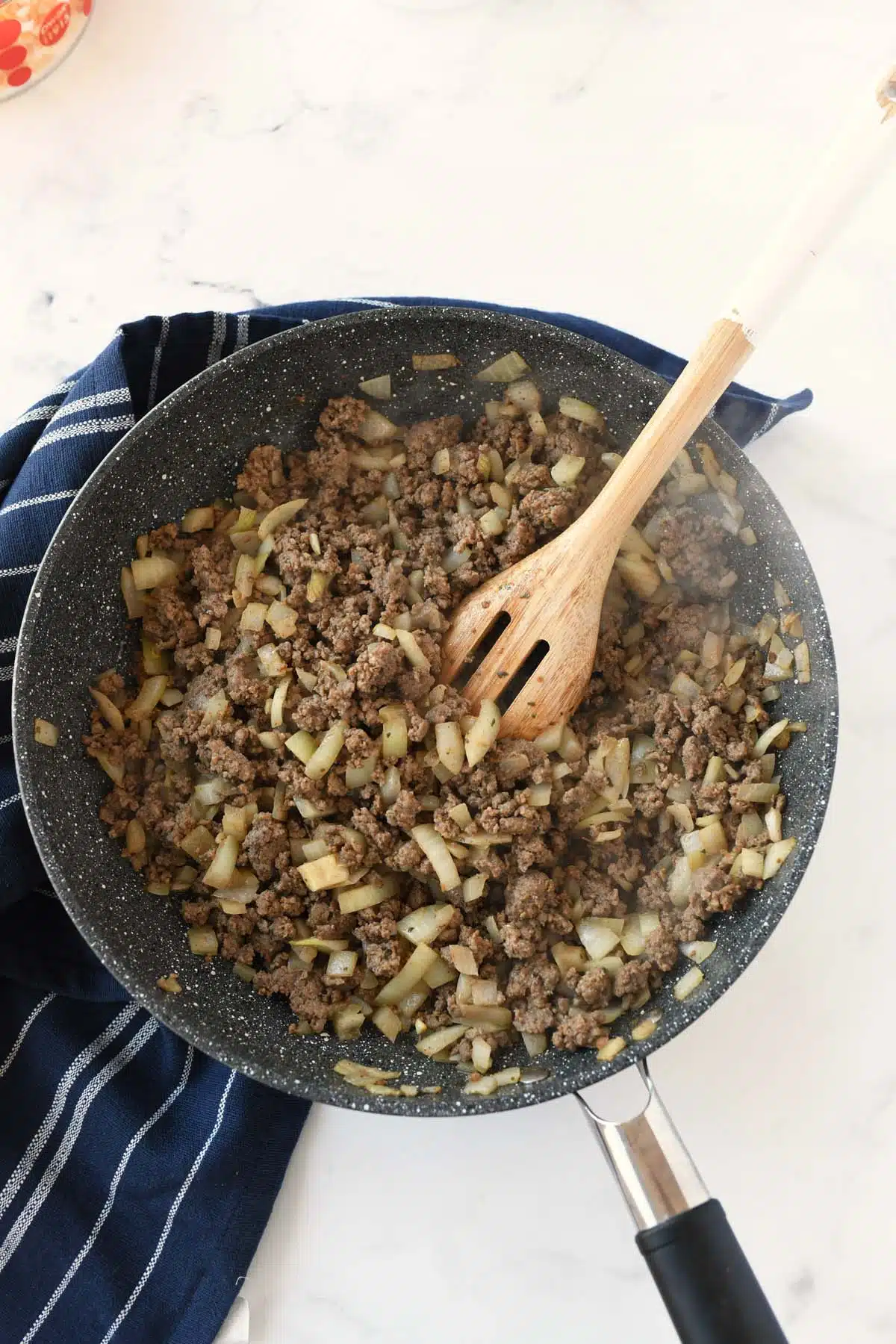 Ground beef with onions in a black skillet.