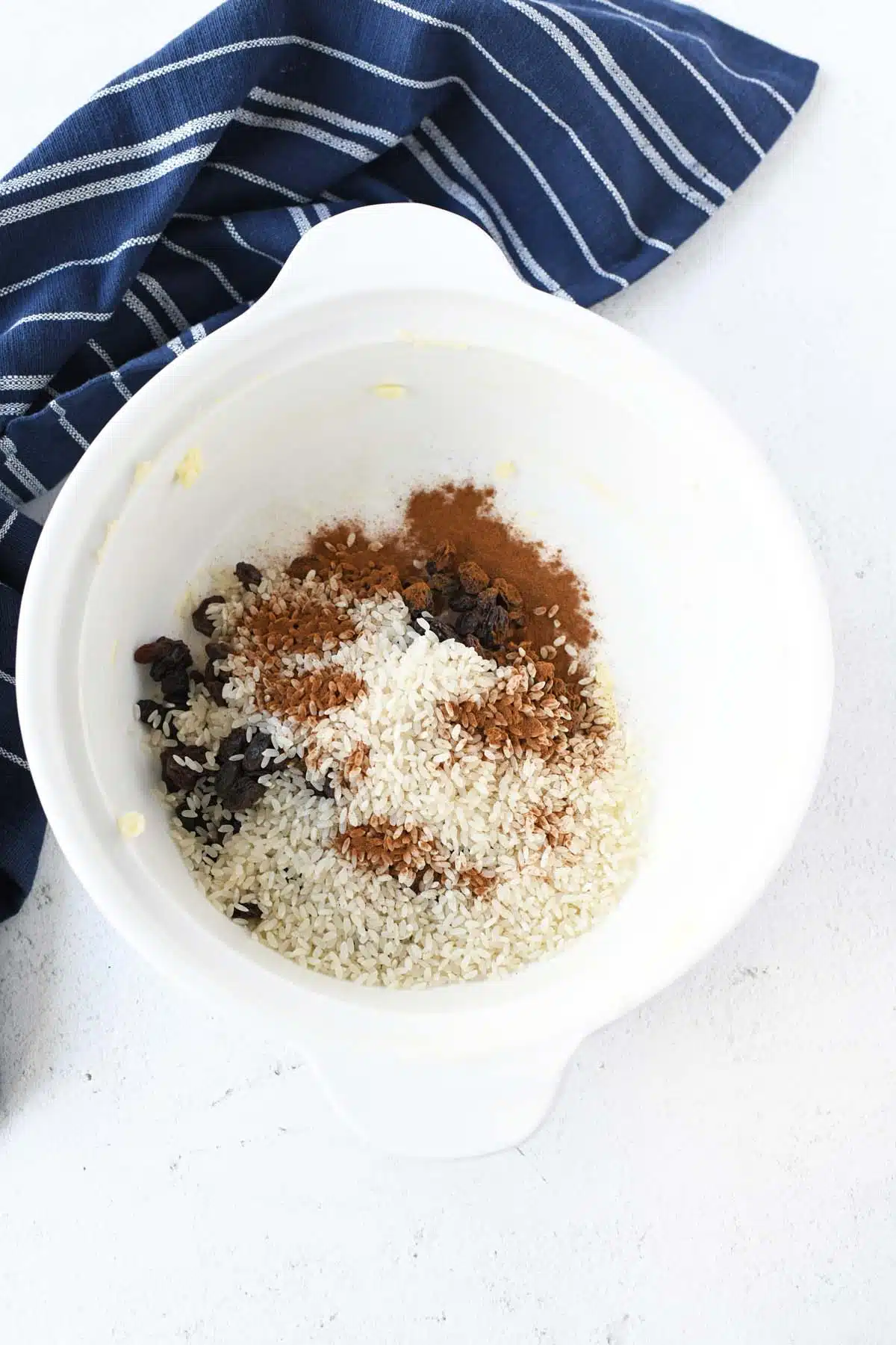 Dry rice pudding ingredients in a white baking dish.