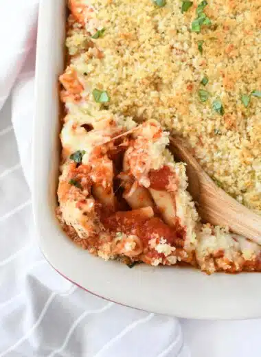 A wooden spoon with chicken parmesan casserole inside.