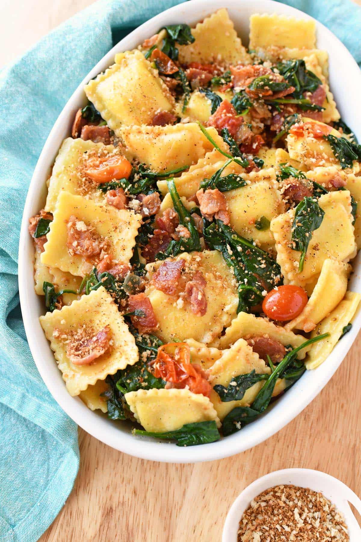 Spinach and tomato in ravioli in an oval dish.