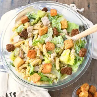Caesar Pasta salad in a glass bowl with croutons.