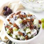 Colorful grape salad with pecans in a white bowl.